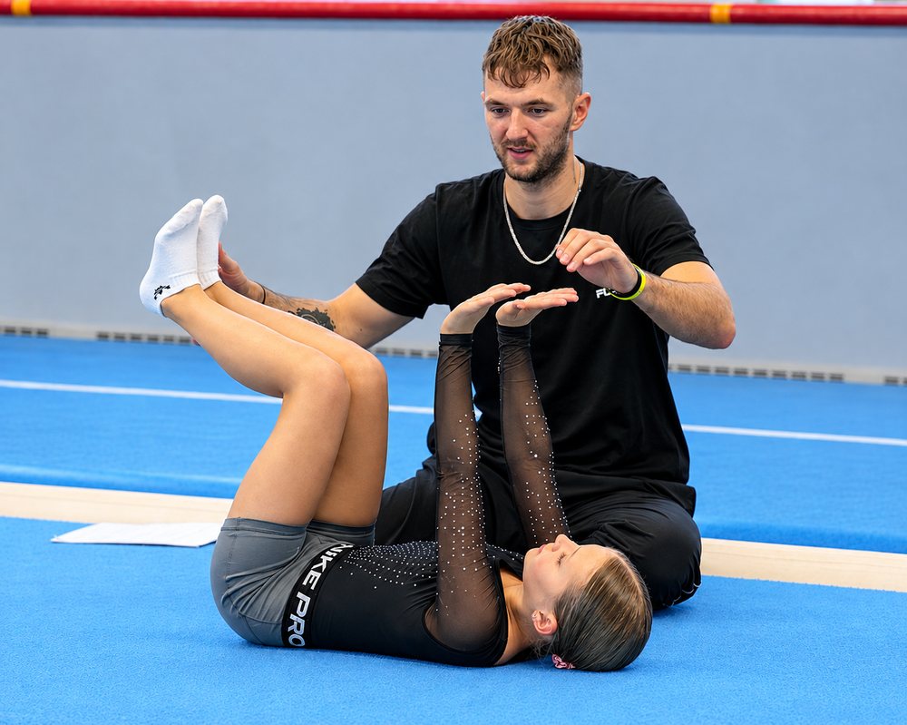 Trener pokazuje zawodniczce pozycję w ćwiczeniu na korpus